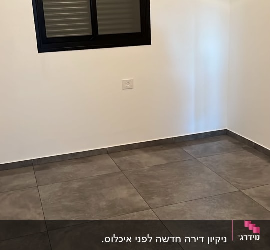 חדר ריק עם חלון ורצפת אריחים אפורה
